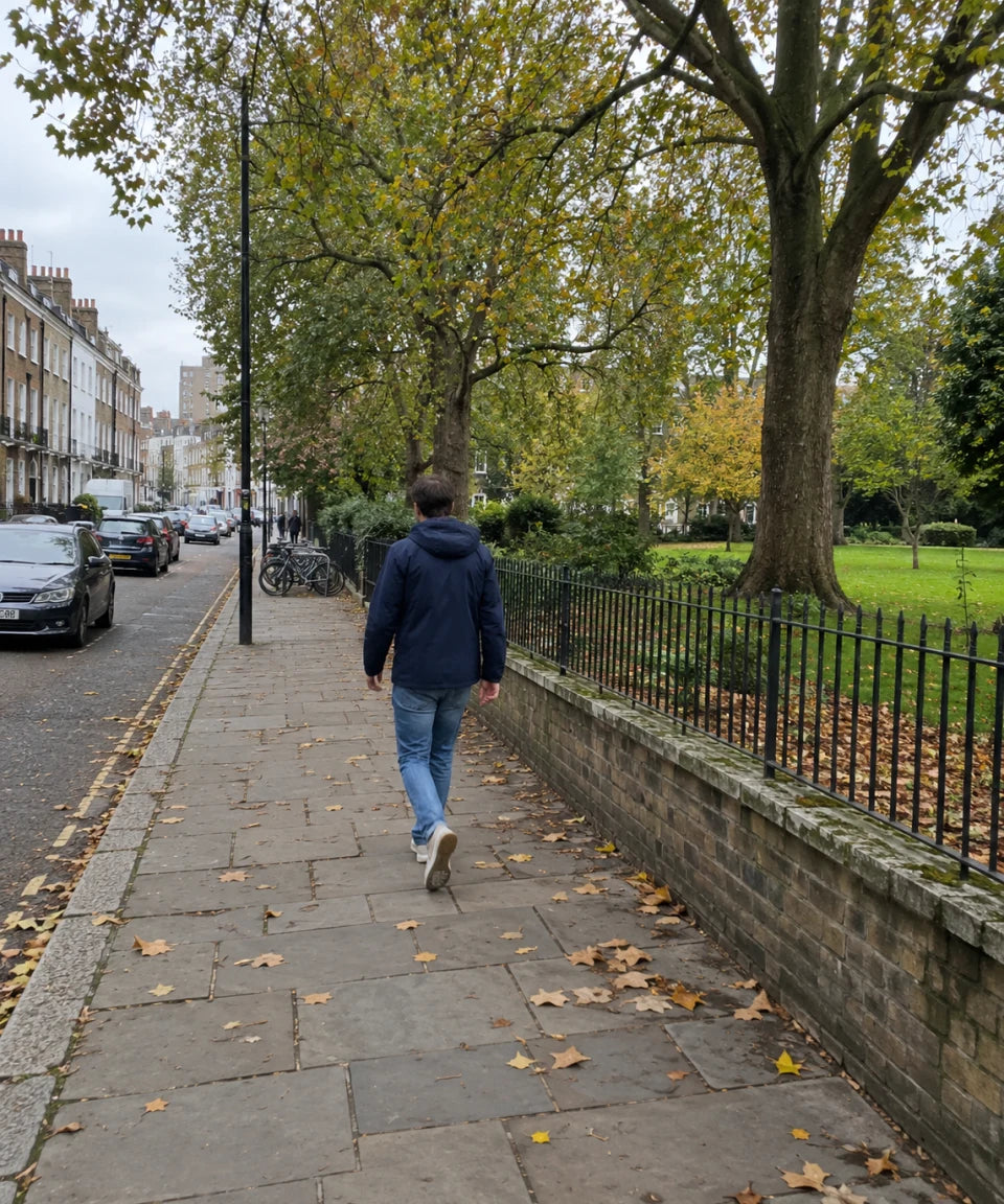 Illustrative scene: a person walks along a tree-lined neighborhood street, seen from a distance.